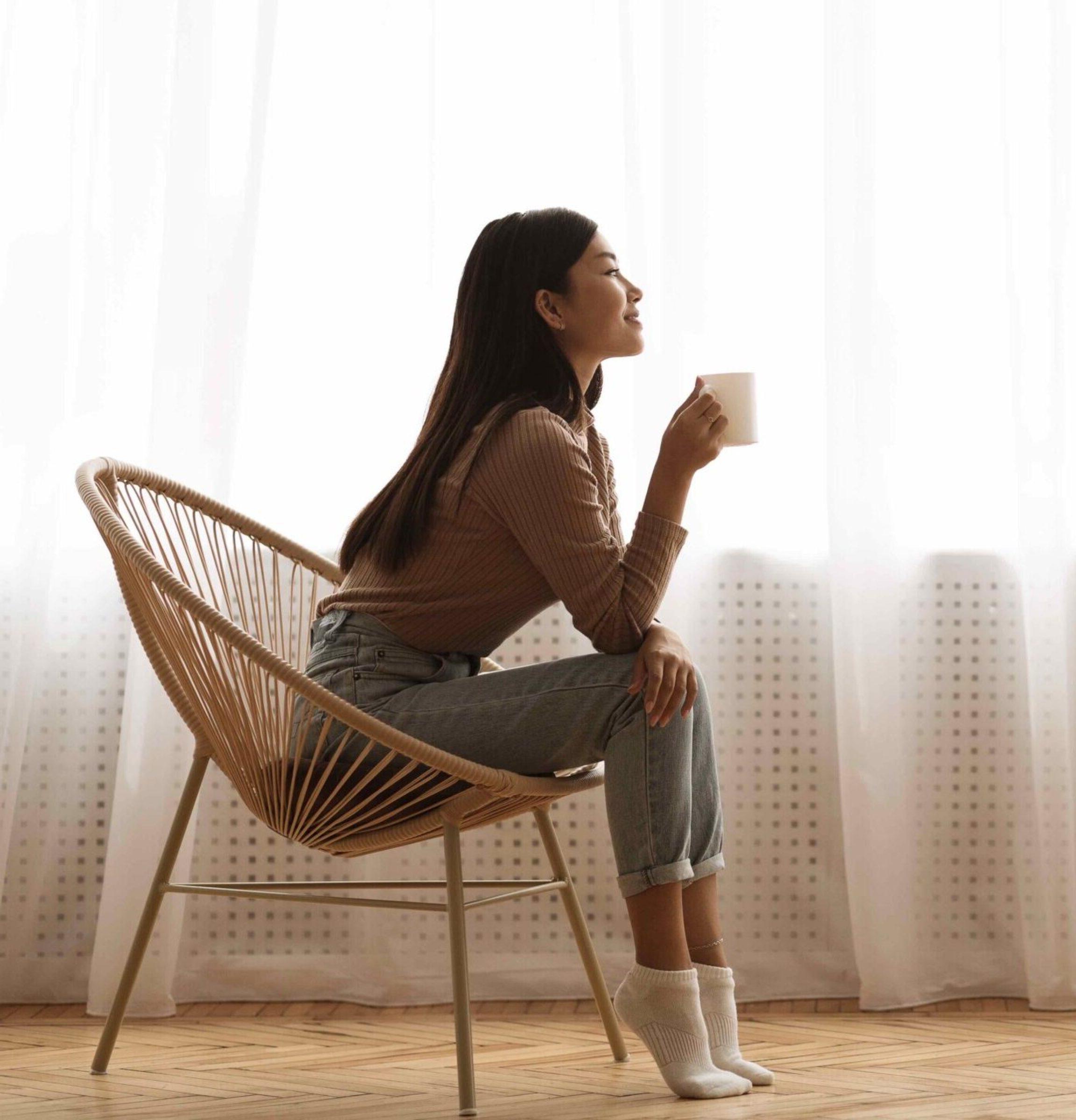 Girl Sitting in Armchair And Enjoying Coffee